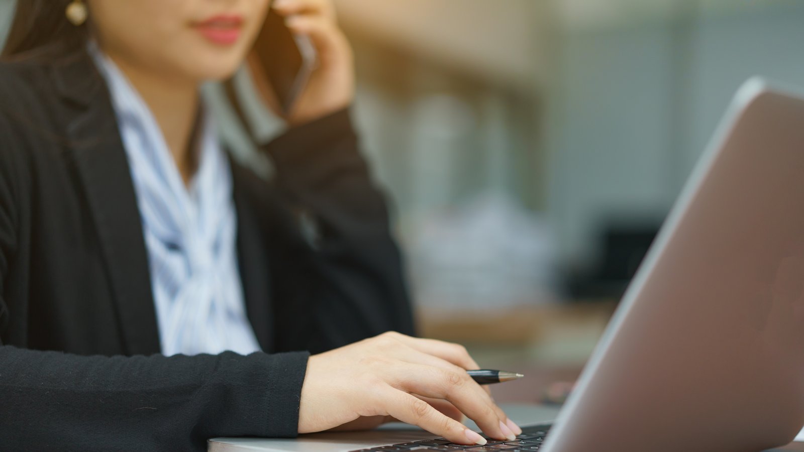 Eine Brokerin sitzt vor ihrem Laptop und telefoniert