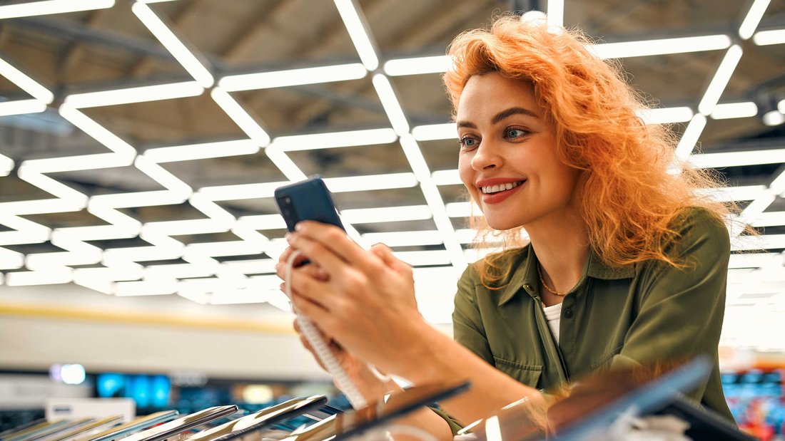 Eine Frau schaut Smartphones in einem Elektrogeschäft an