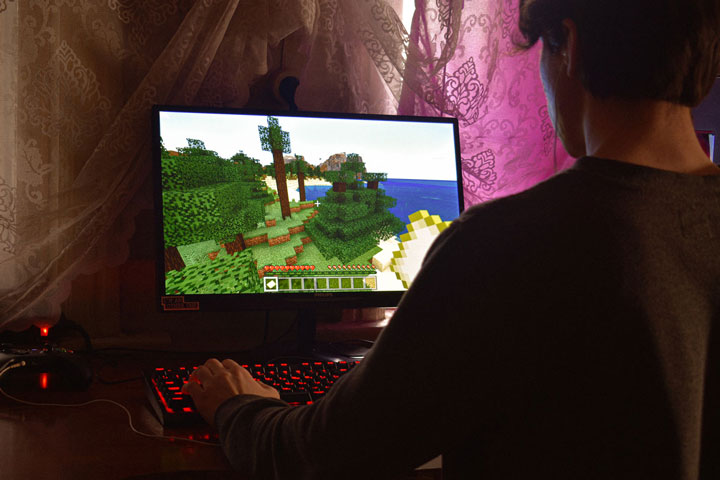 Ein Jugendlicher sitzt vor seinem Computer und spielt Minecraft.