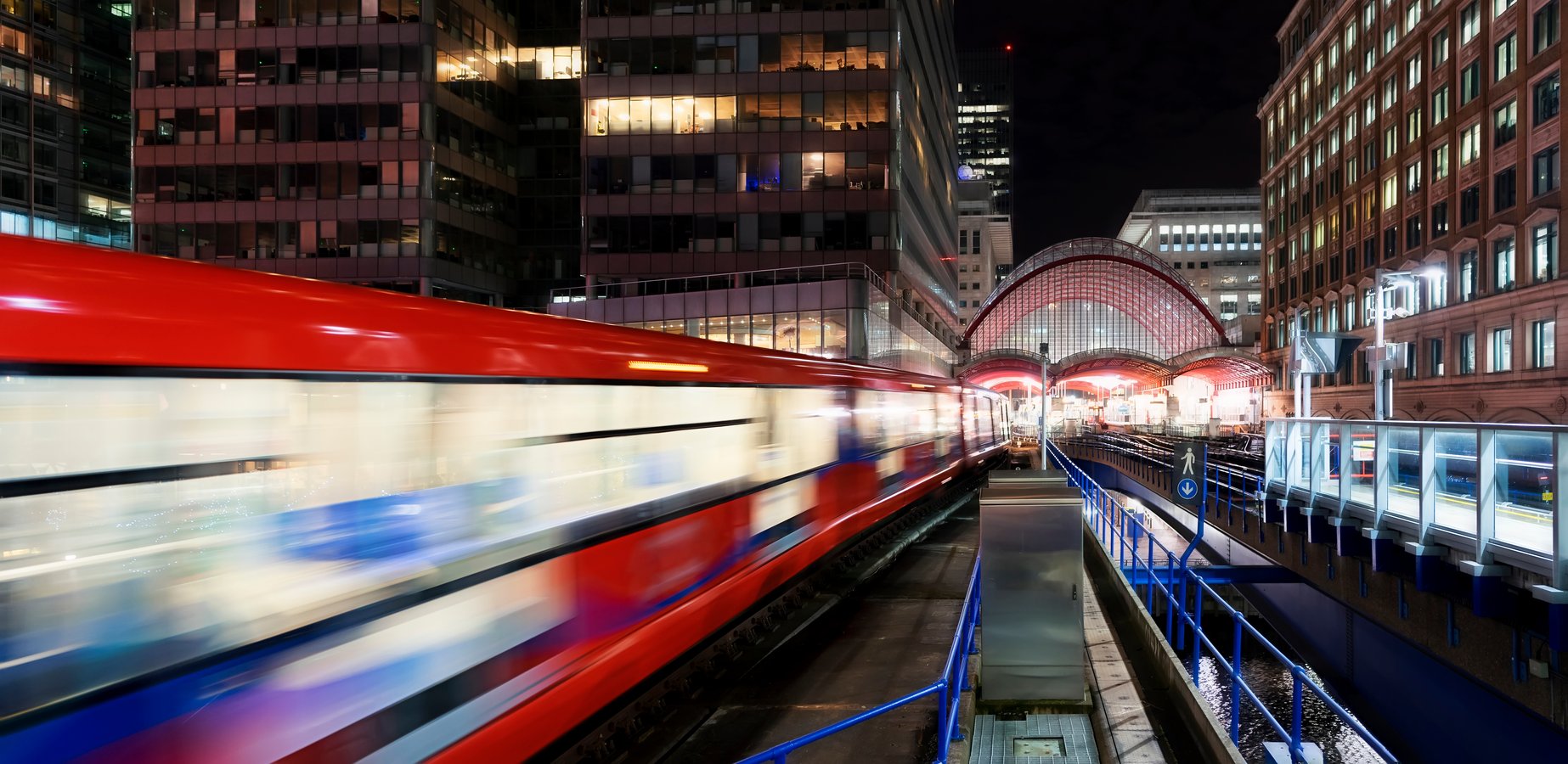 Red train heads out of a train station at night